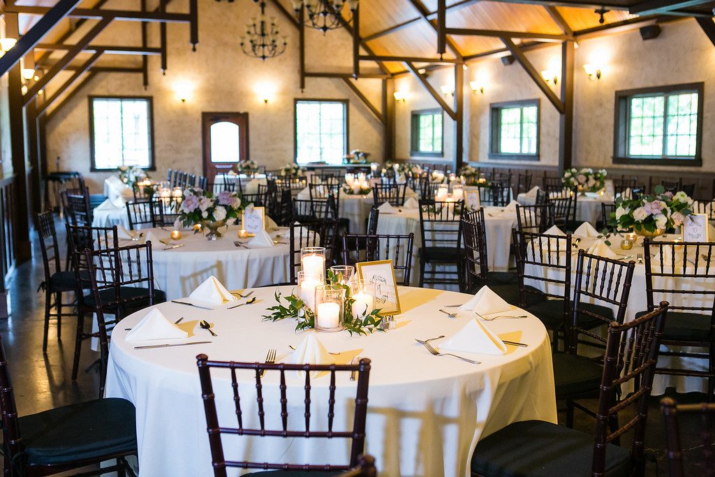 Hollow Hill Event Center Wedding and Event Venue, Weatherford, Texas. Large room with round tables, white table clothes, dark chairs. Candles and greenary in middle of tables